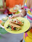 Woman carrying two tacos on a yellow plate
