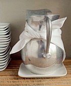 Iced water in a silver jug, pile of white plates beside it