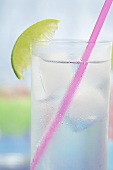 Glas Tonic Water mit Eiswürfeln, Limette und Strohhalm