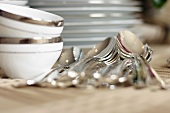 Silver spoons, bowls and pile of plates