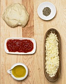 Pizza ingredients: dough, tomato sauce, cheese, olive oil, pepper