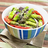 Asparagus salad with red peppers in colourful bowl