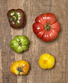 Fünf Heirloom Tomaten auf Holzuntergrund (Draufsicht)
