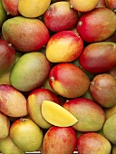 Many whole mangos and a wedge of mango (full-frame)