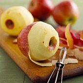 Apples, partly peeled, on chopping board