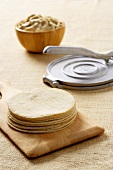 Stack of Freshly Made Tortillas with a Tortilla Press and Bowl of Batter