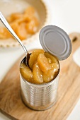 Spoon in a Can of Apple Pie Filling on a Cutting Board, Pie Crust Partially Filled with Apple Filling