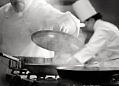 A Chef Lifting a Lid from a Steaming Skillet