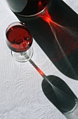 Rotweinglas und Flasche mit Schatten
