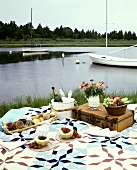 Picnic with fruit, jam and bread rolls on seashore