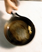 Tossing garlic cloves in pan