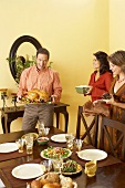 Man and Women Setting Table For Thanksgiving, Man Holding Platter with Roast Turkey