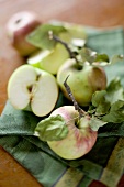 Ganze und halbe Äpfel mit Blättern auf Geschirrtuch