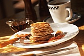 Tall Stack of Swedish Pancakes with Bacon, Pitcher of Maple Syrup and a Cup of Coffee