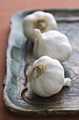 Three Whole Garlic Bulbs on a Wooden Tray