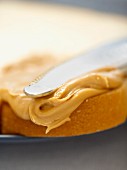 Close Up of Knife Spreading Peanut Butter on a Slice of White Bread