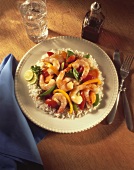 Shrimp and Vegetables Over Rice on a Plate; Fork and Knife