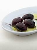 Four Kalamata Olives in a Small Dish with Oil