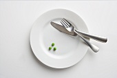 White Plate with Three Green Peas and a Knife and Fork
