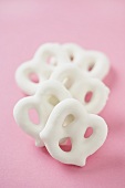 Five Yogurt Covered Pretzels in a Row on a Pink Background