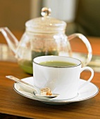 Grüner Tee in Tasse vor Teekanne
