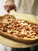 A Chef Holding a Pizza Board with Freshly Cooked Pizza
