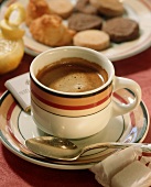 Close Up of a Cup of Espresso on a Saucer with Spoon, Plate of Cookies