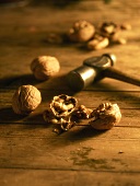 Cracked and Whole Walnuts on a Table with Small Hammer