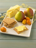Käse, Cracker, Birnen und Kumquats auf Platte