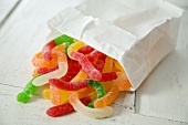 Sweet and Sour Gummy Worms Spilling From a Paper Bag