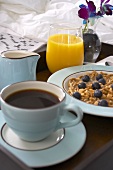 Frühstück im Bett mit Kaffee, Müsli und Orangensaft