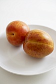 Two Organic Pluots on a White Plate