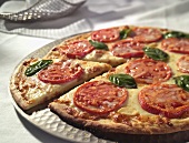 Pizza mit Tomaten und Basilikum, angeschnitten