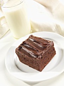 A Chocolate Brownie with Chocolate Frosting and a Glass of Milk