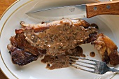Strip Steak mit Pfeffersauce auf Teller mit Besteck