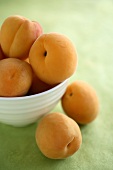 Mehrere frische Aprikosen in und neben einer Schale