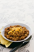 Bowl of Lentil Chili Topped with Orange Melted Cheese