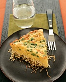 Slice of Baked Spaghetti Pie with Peas; Glass of Water