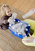 Frau und kleines Mädchen sammeln Plastikflaschen fürs Recycling