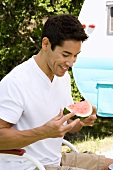Man Sitting in an Outdoor Chair with a Wedge of Watermelon