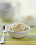 A scoop of caramel ice cream in a white bowl