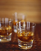 Brauner Rum mit Eiswürfeln in drei Gläsern