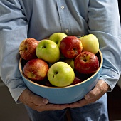 Man Holding a Bowl of Red and Green Apples