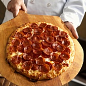 Chef Holding Pepperoni Pizza on Wooden Peel