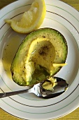Half an Avocado with Cracked Pepper Dressing on a Plate with Spoon