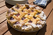 Lattice Top Cherry Pie with Powdered Sugar on Picnic Table