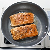 Two Salmon Fillets Cooking in Skillet
