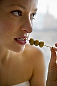 Frau isst grüne Oliven vom Zahnstocher
