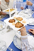 Person Holding Plate of Latkes at Chanukah Table