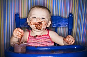 Baby isst Schokoladenpudding